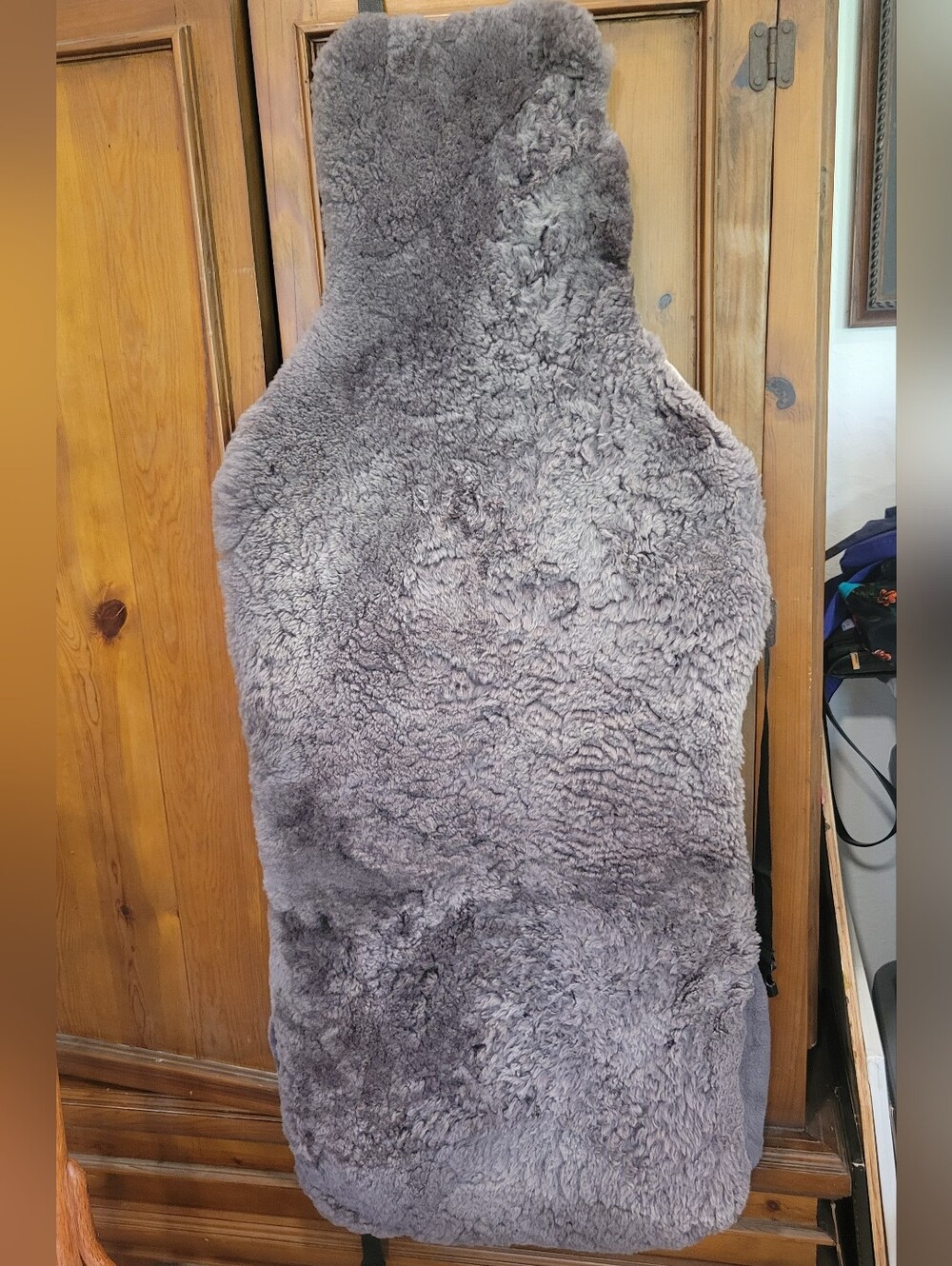 Grey fluffy item is a sheepskin car seat cover designed for f